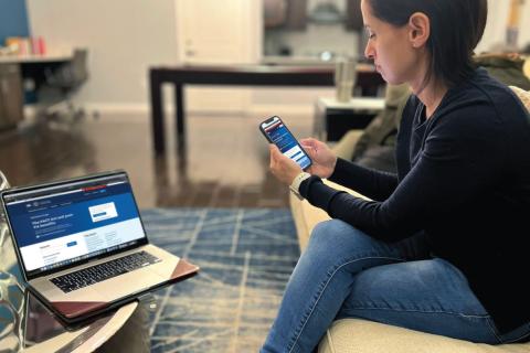 Woman with a mobile phone and computer, signing in to VA.gov.