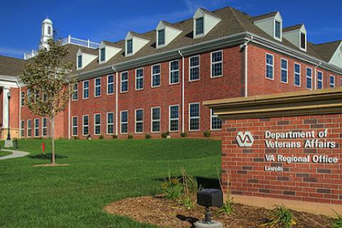 Front of Lincoln VA Regional office and front sign. Red brick building with white columns at the entrance. 