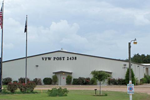 Large white building. VFW Post 2438 in black lettering. 3 Flag poles and a sign mentioning bingo.