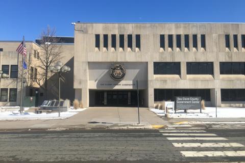 Cement building with Eau Claire County Courthouse Emblem above the four door entrance. Walk in the main entrance and look for County Veteran Services.