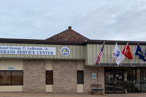 A brown building with military branch flags at the entrance