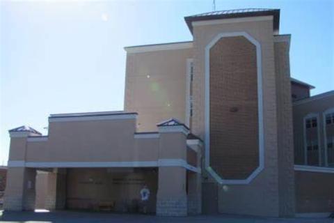 A tan two-story building with a large entrance area with sliding glass doors