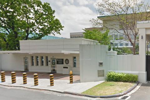 white single story building behind a row of security posts next to a black gated entrance