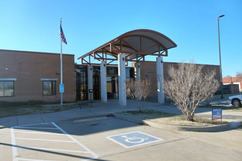 An entrance to a large brick building with a large awning supported by six concrete pillars