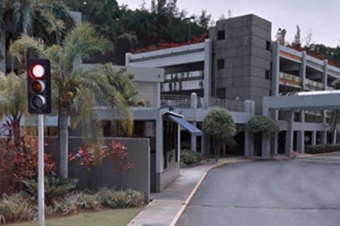 a multiple story concrete building with an entrance marked by a concrete wall at an intersection 