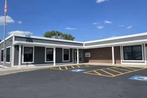 "L" shaped building with brick and lap siding. Entrance at inside corner.