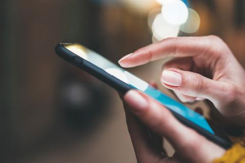 Female hands holding a mobile phone as if they are texting someone.