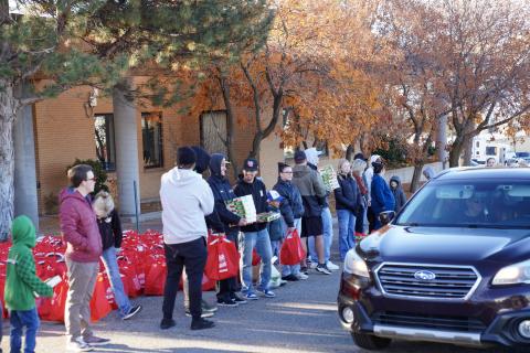People stand by hundereds of meal kits in red bags, prepared to hand out at the Ken Garff Automotive Drive Out Hunger event