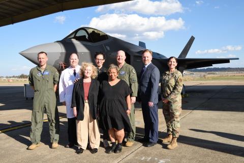 group of VA employees and military standing in front of a fighter plane