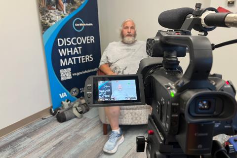 Veteran Charles Barlow in front of a Whole Health banner.