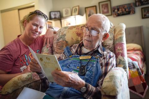 nurse and veteran reading a birthday card together on his birthday in veteran's home