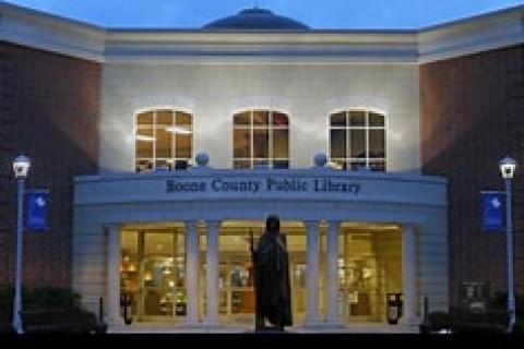 Illuminated Boone County Public Library at night with a statue in front.