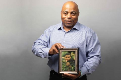 Veteran Charles Bazier displaying a photograph from when he was active duty.