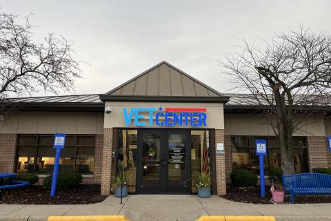 Vet Center building with blue and red logo, surrounded by trees and blue benches.