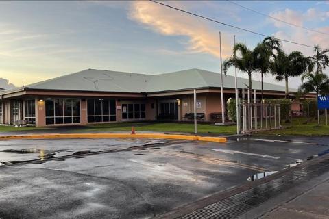 Wet parking lot in front of a building with palm trees.