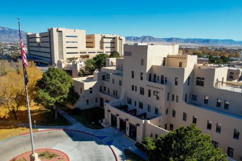 Aerial view of a large beige building, with flag and trees.