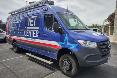 Blue and gray van with "VET CENTER" and star graphic parked in lot.