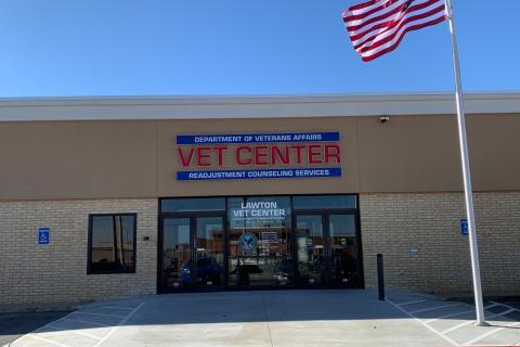 Vet Center facade with glass doors, American flag, and blue sky.