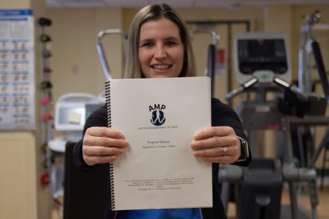 Woman in a hospital room holding a spiral bound booklet.