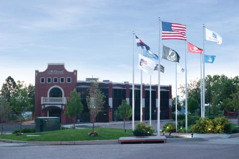 American and state flags in front of a brick building.