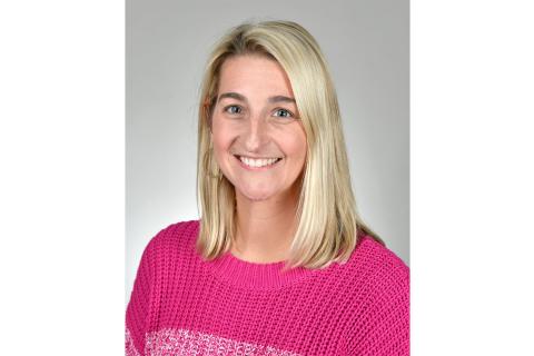 Portrait of a woman with blonde hair wearing a pink sweater.
