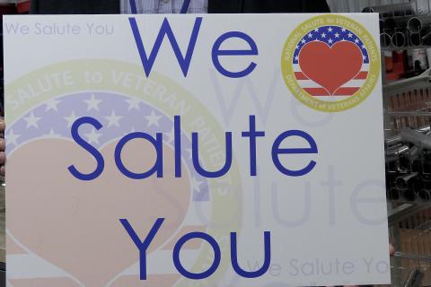 Sign reads "We Salute You" with American flag and heart.