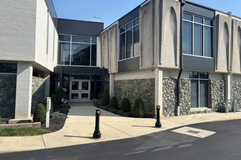 Modern building with glass windows, stone facade, and entrance walkway.