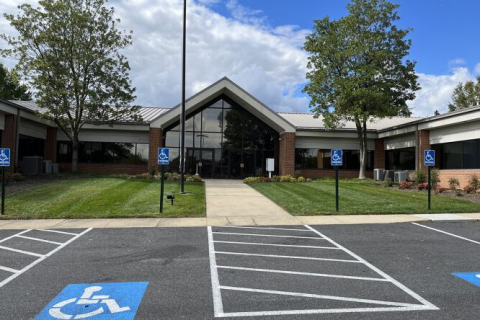 Entrance to a public building with parking spaces and handicap signs.