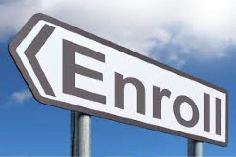 Sign with arrow pointing left and the word "Enroll" written in black on white background.