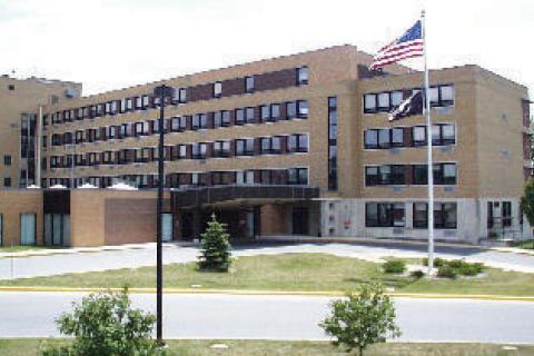 Multi-story building with flag and lawn in front.