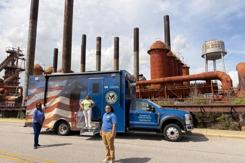 Two women in front of a blue truck, one woman on the truck.