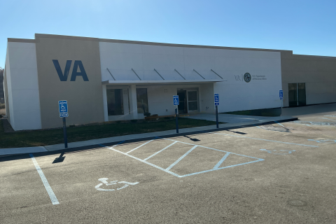 VA building with parking lot, blue signs, and wheelchair symbol.