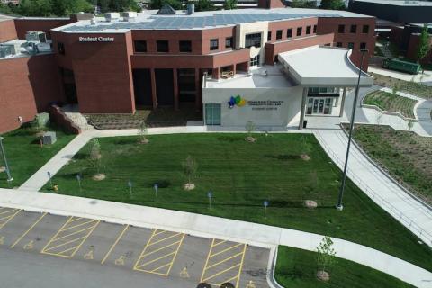 Aerial view of a modern building with green lawns and solar panels on the roof.