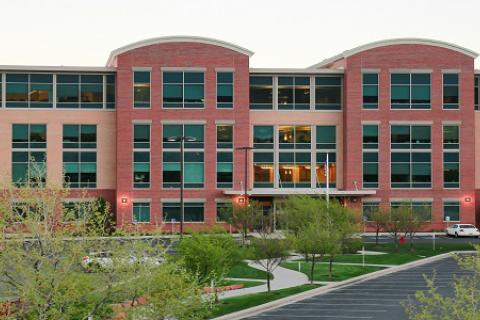 Modern office building with glass windows, and two arched features that extend above building roof line. 