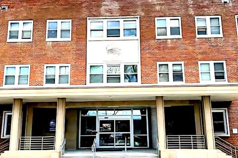 Brick building with many windows and glass entrance.