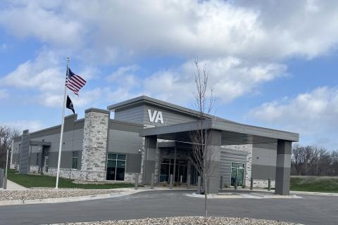 Modern VA building entrance with flags and a barren tree.