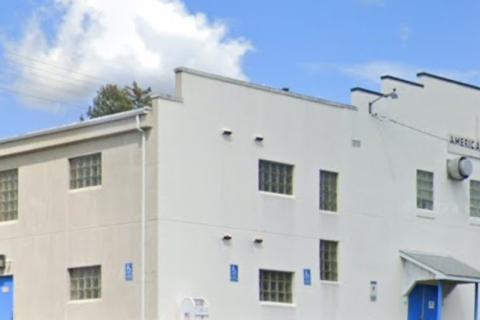 White building with blue doors and windows under blue sky with clouds.