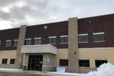 Modern brick office building with snow on ground, cloudy sky.