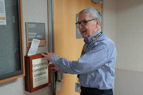 A man in a blue shirt opens a comment box on a wall.