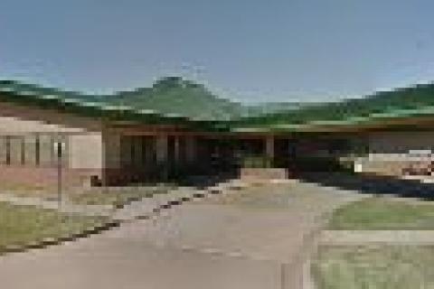 Exterior of a beige building with green roof and driveway.