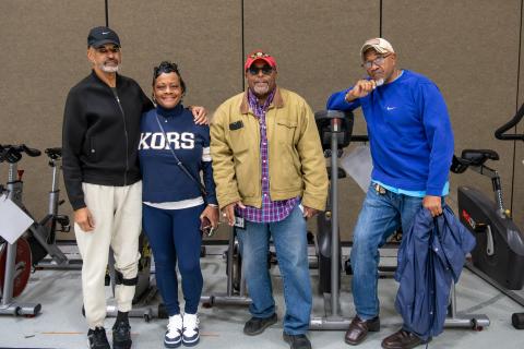 Four people standing together in a gym with exercise bikes.