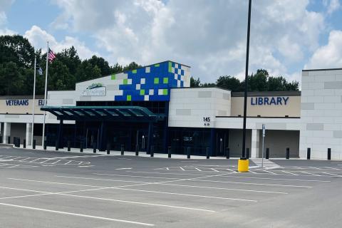 Empty parking lot in front of large white building.