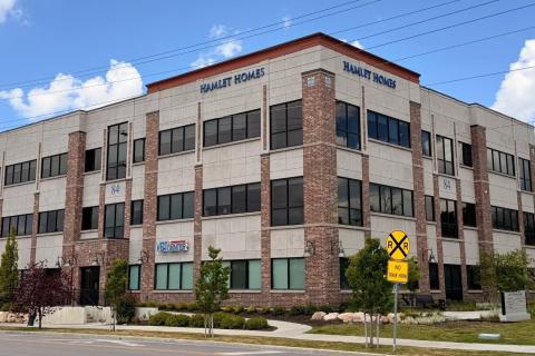 Salt Lake Vet Center located in a modern office building with many windows, greenery, and a yellow yield sign.