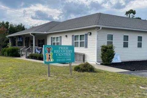 Green sign in front of white building on green grass.