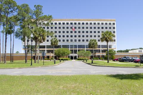Naval Hospital Pensacola and a flag, surrounded by trees and grass.