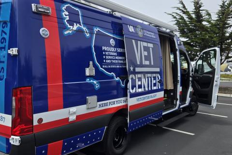 Blue and red van with "Vet Center" text and US map graphic parked in lot.