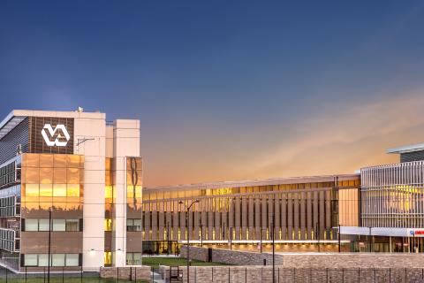 Modern building with VA logo at sunset, featuring glass facades and contemporary design.