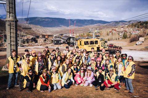 Group photo of people in yellow jackets at ski resort.