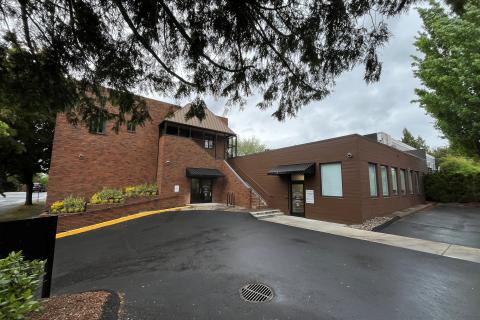 Brown office building with black awnings and empty parking lot.
