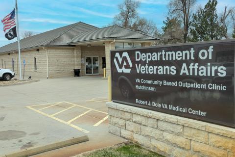 Department of Veterans Affairs sign in front of beige building with flag.